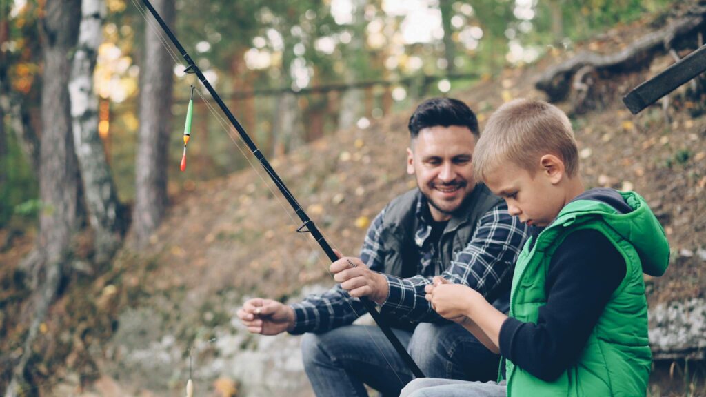 Father and son enjoy a bonding fishing trip in a beautiful outdoor forest setting.